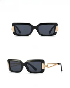 Detail view of black rectangular sunglasses with hollow gold metal temples and geometric frame