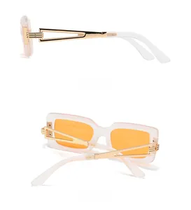 Detail of square frosted white sunglasses with gold hollow metal temples and orange lenses