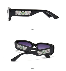 Détails des lunettes de soleil carrées noires avec motifs papillons colorés sur les branches