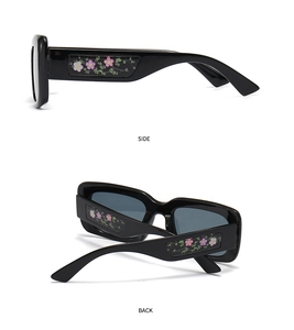 Detail view of black square sunglasses with decorative pink and green floral temples