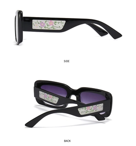 Detail view of black square sunglasses with floral patterns on temples and gradient lenses
