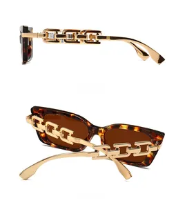 Detail view of tortoiseshell sunglasses with chunky gold chain temples and brown lenses