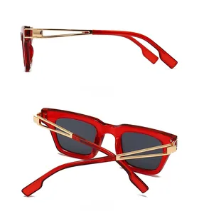 Vue détaillée de la monture carrée rouge et des branches en métal doré des lunettes de soleil