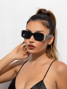 Gros plan de lunettes de soleil rectangulaires noires avec détails dorés sur un mannequin
