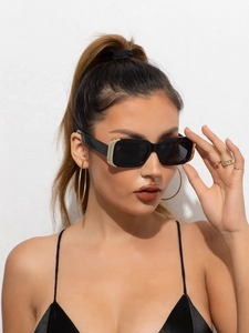 Détail de lunettes de soleil carrées noires avec charnières dorées sur modèle