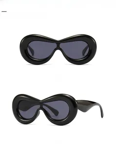 Detail of chunky puffy polygon sunglasses with thick black frames and dark grey lenses