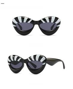 Futuristic cat-eye sunglasses with bold black and white radial stripes from dual angles