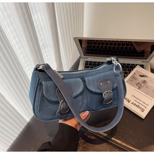 Detail of blue denim shoulder bag showing vintage silver buckles and functional front pockets