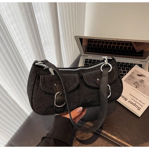 Detail of black denim shoulder bag featuring front pockets and silver buckles