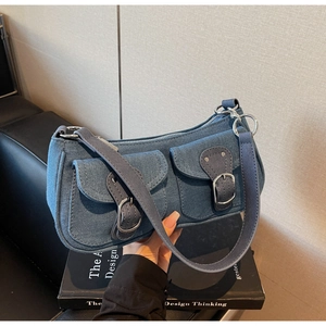 Detail of denim shoulder bag with silver hardware buckles and two front pocket flaps