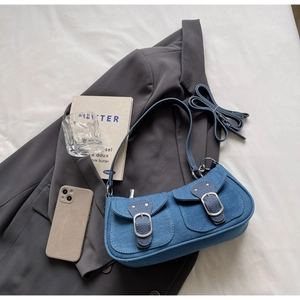 Detailed view of blue denim shoulder bag with silver buckles and adjustable strap