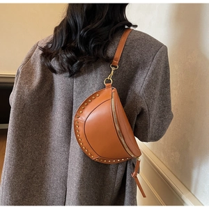 Close-up of vintage brown leather chest bag with golden rivet trim on grey blazer