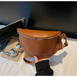 Detailed view of a brown leather crescent bag with retro rivets on a desk setting