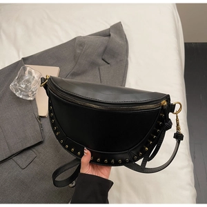 Detail of black semi-circular crossbody bag featuring golden rivets and premium texture