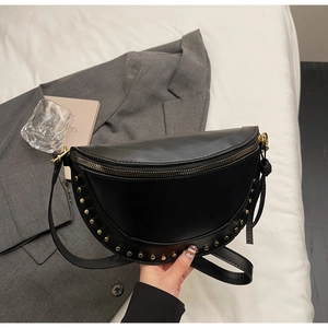 Macro shot of black crescent bag with golden rivet studs on smooth synthetic leather surface