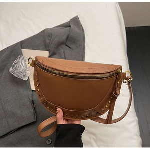 Close-up of brown crescent crossbody bag with gold rivet details and leather texture