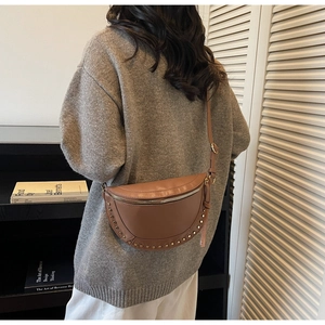 Detail of brown leather crossbody bag with silver rivets worn by a model on back