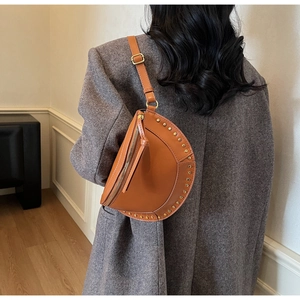 Detailed view of vintage brown leather saddle bag with gold studs and adjustable strap