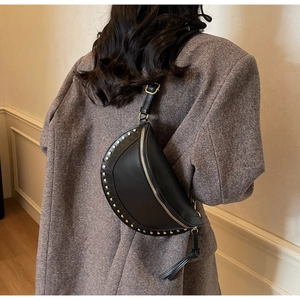 Detail of vintage rivets on black crescent leather bag worn with grey blazer