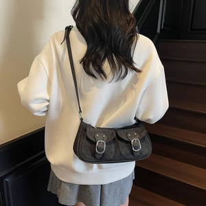 Fashionable dark denim crossbody bag with adjustable strap and silver buckles