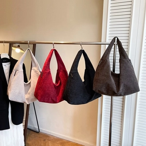 Minimalist canvas hobo bags in four colors shown hanging on a display stand