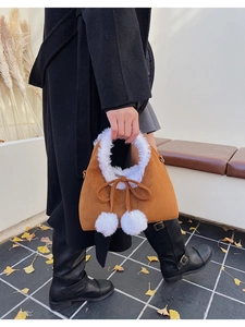 Detail of plush faux suede handbag with soft white fur trim and cute pom-poms charms