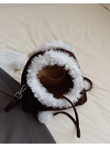 Detailed view of the brown faux suede interior with plush lining and white pom-pom accents