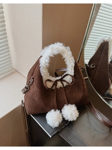 Detail of plush winter crossbody bag featuring faux fur trim and decorative pom poms