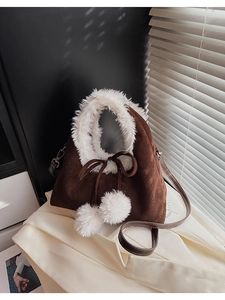 Close-up of brown suede bag featuring plush white fur trim and fluffy pom-pom details