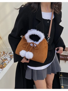 Brown faux suede crossbody bag with plush white trim and fluffy decorative pom-poms