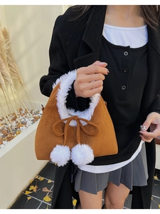 Close-up of brown suede handbag with white faux fur trim and cute pompom bow detail