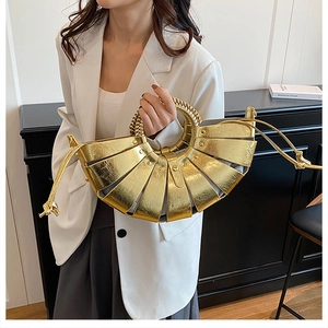 Detail of woven round handle and pleated metallic gold bag held by a model