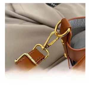 Detail of adjustable brown leather shoulder strap with gold-tone hardware and buckle