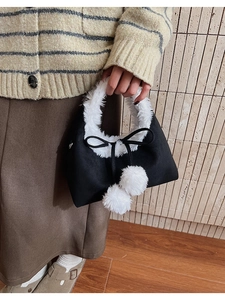 Detail of plush triangle bag with white faux fur trim, cute pom-poms, and black bow