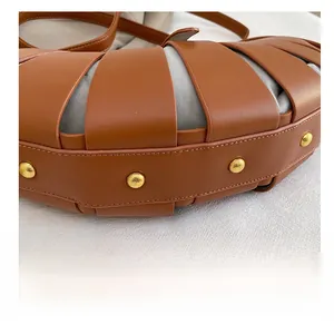 Detailed macro view of woven brown leather bag with five gold protective metal studs on base