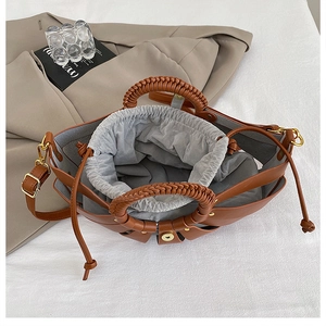 Top view of brown fan-shaped tote with woven handle and drawstring inner pouch