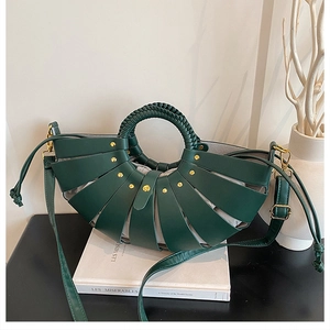 Detail of dark green woven bucket bag with gold rivets, drawstring pouch and leather strap