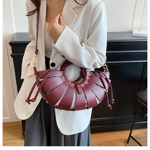 Detail view of burgundy woven bucket bag with gold studs and beige drawstring lining