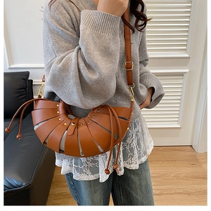 Detail of caramel leather basket bag with curved layered design and drawstring accents