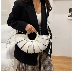 Detailed view of white woven bucket bag with circular handle and gold rivets on black suit