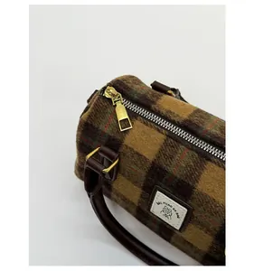 Detail of golden metal zipper and brown plaid wool texture on the Boston bag