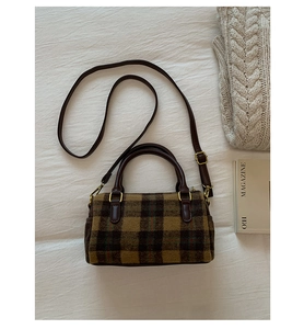 Retro yellow plaid wool Boston bag with brown leather handles on a cozy fabric background