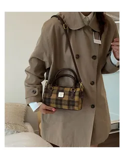 Detail view of brown plaid Boston bag with leather handles shown on a model
