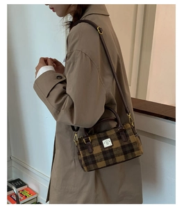 Detail of vintage plaid wool boston bag with brown leather handles and golden metal buckles