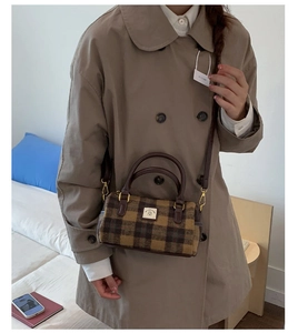 Close-up of khaki plaid woolen Boston bag with leather handles and white logo patch