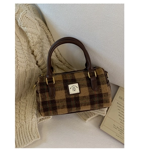 Close-up of vintage plaid Boston bag with leather handles on a beige knitted sweater