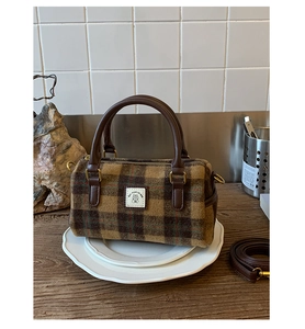 Close-up of retro plaid wool Boston bag with brown leather handles and brand tag detail