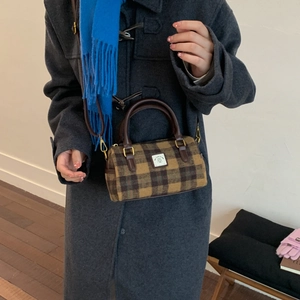 Retro plaid Boston bag in brown wool with leather straps, worn by a model in a grey coat