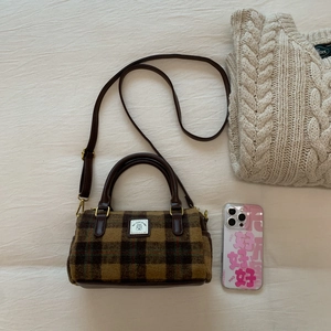 Vintage brown plaid wool Boston bag with leather handles and adjustable strap on white fabric