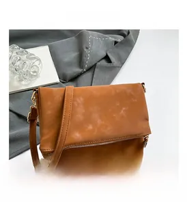 Detail view of caramel brown saddle bag showing leather flap and metal zipper design